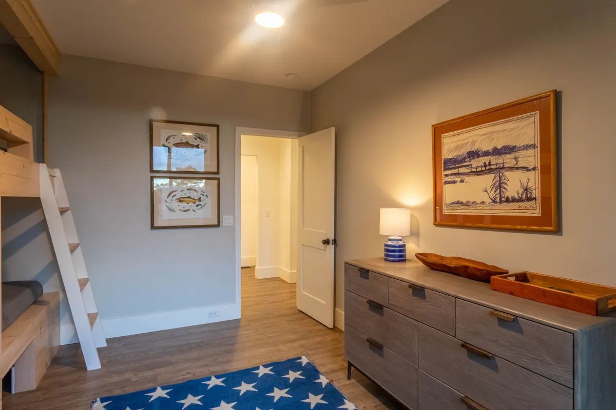 A warmly lit bunk bed nook with a playful, star-patterned rug and framed artwork, creating an inviting spot for kids or families to relax, play games, or share stories together.