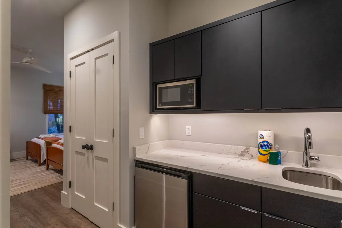 A modern kitchen scene with sleek black cabinetry, stainless steel appliances, and a sunlit window. The open countertop provides ample space for preparing meals, baking, or enjoying informal gatherings.