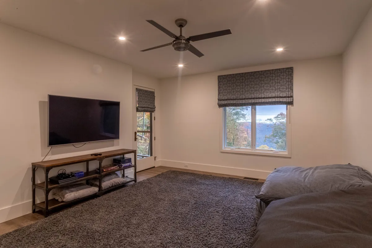 A cozy, comfortable living area featuring a large window that brings in natural light, a plush seating arrangement perfect for gathering, and a television as the focal point—ideal for movie nights or casual relaxation.